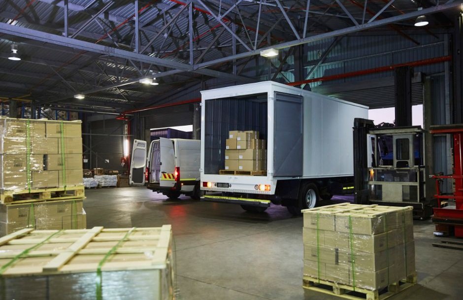 Interior de almacén logístico con camión de carga y palets de mercancía